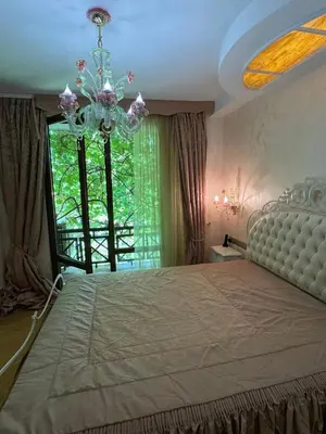a bedroom with a large bed with a chandelier at Апартамент в Лозенец, Oasis Resort and Spa in Lozenets