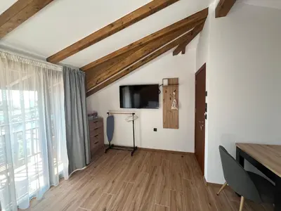 a living room with wooden ceilings and a flat screen tv at Къща за гости Сирената in Sozopol