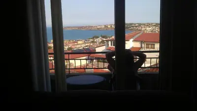 a person sitting in a chair looking out a window at Guest House Polikseni in Sozopol