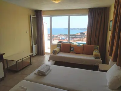 a hotel room with two beds and a large window at Guest House Polikseni in Sozopol