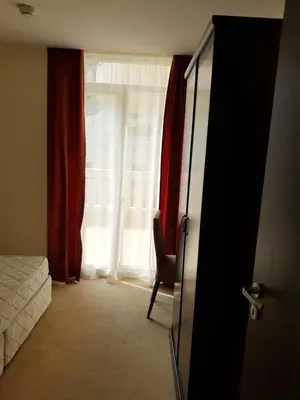 a room with a window with a chair and a bed at Сънсет резорт Поморие in Pomorie