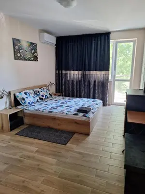a bedroom with a bed and a large window at Бобс апартаменти 1 in Kiten