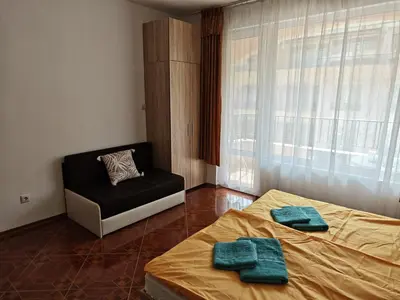 a bedroom with two beds and a chair and a window at SUN LIGHT Slnečné pobrežie in Sunny Beach