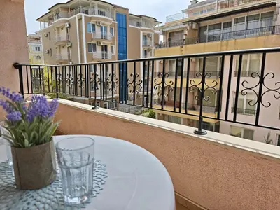 a table with a glass on a balcony with buildings at SUN LIGHT Slnečné pobrežie in Sunny Beach