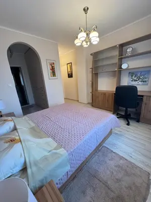 a bedroom with a large bed and a chair at Эстебан с 2 спальнями in Nesebar