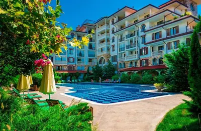 a hotel with a pool and chairs and umbrellas at Эстебан с 2 спальнями in Nesebar