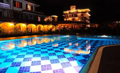 a swimming pool with blue tiles on it at night at Эстебан с 2 спальнями in Nesebar