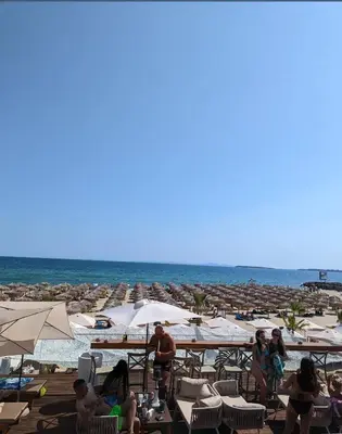 a group of people sitting on a beach with umbrellas at Kombani 3 in Sveti Vlas