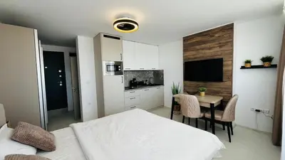 a bedroom with a bed and a table and a kitchen at JADORE Secret Garden Panoramic Studio in Sunny Beach