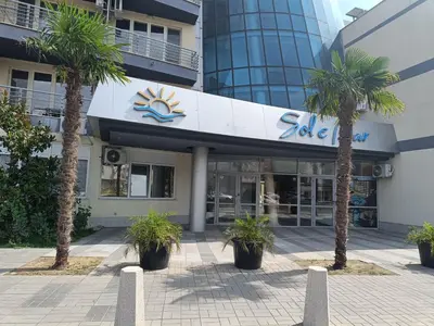 a building with palm trees in front of it at Sol e Mar Sunny Beach in Sunny Beach