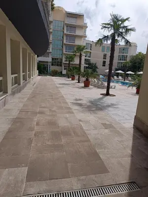 an empty sidewalk in a building with a palm tree at Sol e Mar Sunny Beach in Sunny Beach