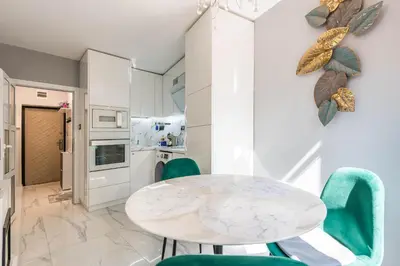 a white dining room with a white table and green chairs at Dany's Apartments in Varna City