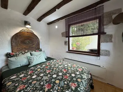 a bedroom with a bed with a floral bedspread and a window at Villa Filistrina in Yasna Polyana