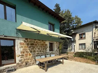 a wooden bench sitting outside of a building with an umbrella at Villa Filistrina in Yasna Polyana
