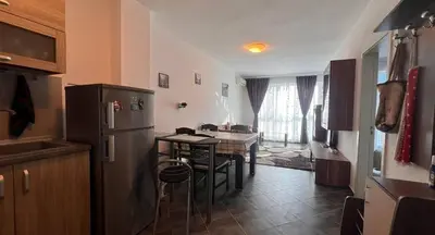 a kitchen with a refrigerator and a table with chairs at Двустаен апартамент с морска панорама в Blue Bay Palace in Pomorie