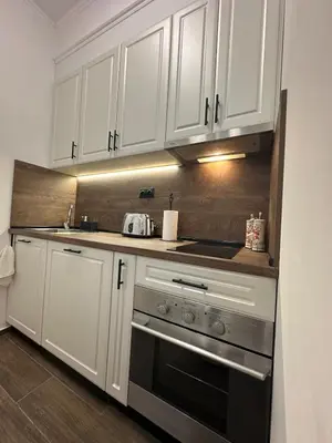 a kitchen with white cabinets and a stove at Апартамент за нощувки и отдих in Burgas City