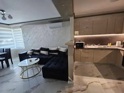 a kitchen and a living room with a couch and a table at Small Central Flat - Walk to Station & Cathedral in Varna City