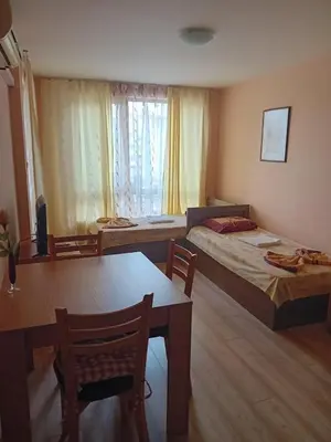 a room with two beds and a table and a dining room at Двустаен апартамент във Виго Панорама Несебър in Nesebar