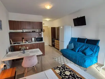a living room with a blue couch and a kitchen at complex Rose Residence Studio in Sunny Beach