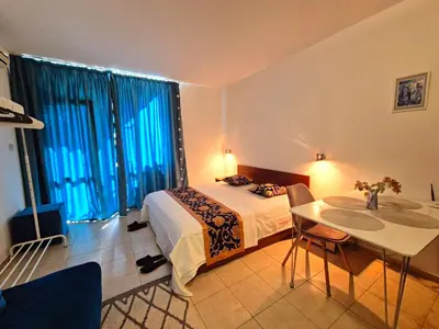 a bedroom with a bed and a table and windows at complex Rose Residence Studio in Sunny Beach