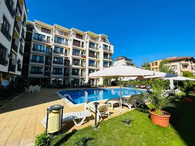 a large apartment building with a swimming pool and umbrella at Amber Beach in Sunny Beach