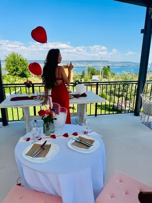 a woman standing on a balcony with a table with food at Sea Sky House in Varna City