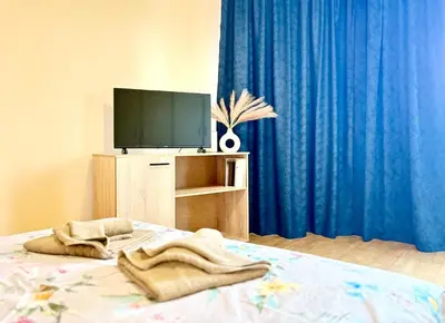 a bedroom with a bed with a television and blue curtains at Varna Thermae Loft in Varna City