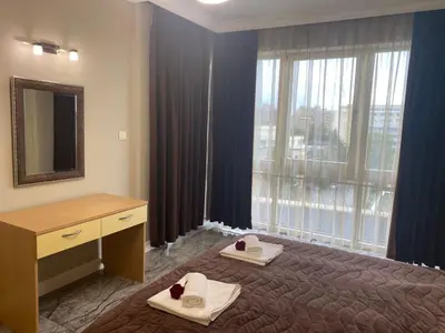 a bedroom with a bed and a dresser and a window at Sol e Mar Deluxe Apartment in Sunny Beach
