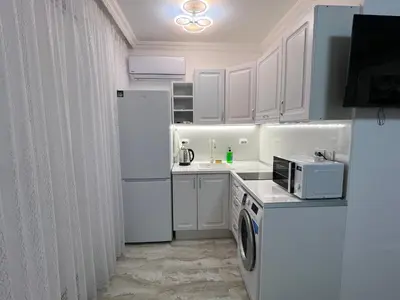 a white kitchen with a refrigerator and a microwave at Студия Магнолия 6, Солнечный берег Болгария in Sunny Beach