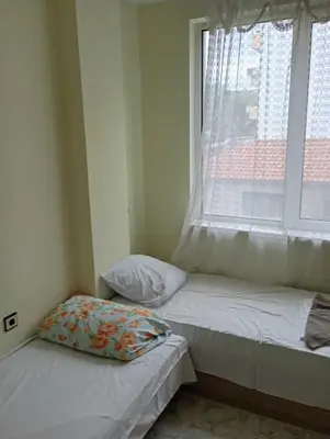 two twin beds in a room with a window at Апартамент планина in Varna City
