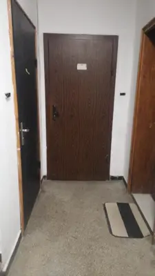 an empty hallway with a wooden door and a rug at Апартамент център in Varna City