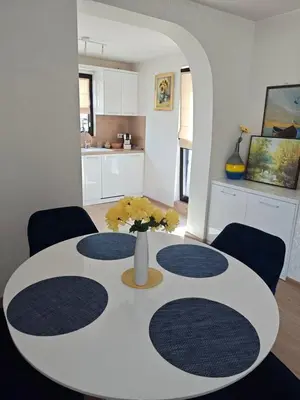 a white dining room table with a vase of flowers on it at Trend Apart in Burgas City