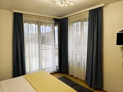 a bedroom with a bed and two large windows at Trend Apart in Burgas City