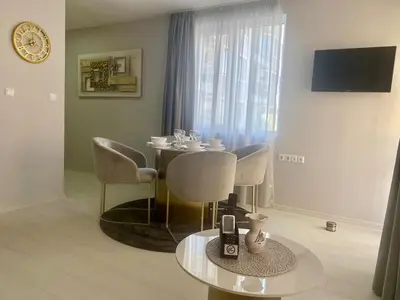 a dining room with a table and chairs and a clock at J'Adore Secret Garden, Deluxe Apartment in Sunny Beach