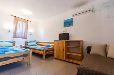 a room with two beds and a tv and a couch at Бунгала Гнездото Bungalows The Nest Lozenets 2 in Lozenets