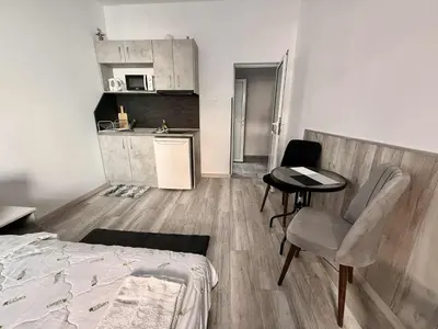a room with a bed and a table and a kitchen at Sun in Varna City
