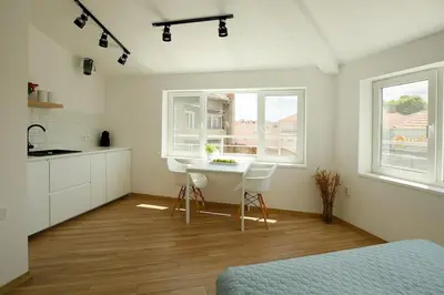 a bedroom with a kitchen and a table and two windows at The Corner Studio in Varna City