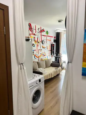 a living room with a washing machine and a couch at Студия Авангард in Sunny Beach