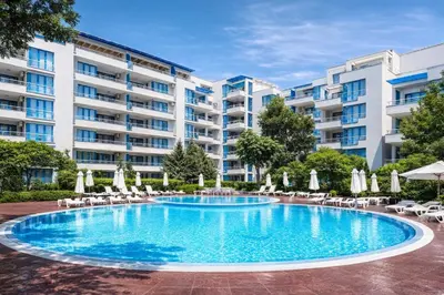 a swimming pool with chairs and umbrellas in front of a building at Excelsior Apartment in Sunny Beach