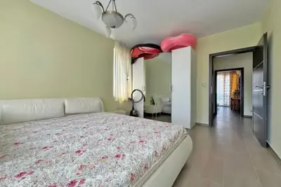a bedroom with a large white bed with red sheets at Apartments Nessebar in Nesebar