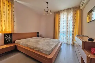 a bedroom with a large bed and yellow curtains at Apartments Nessebar in Nesebar
