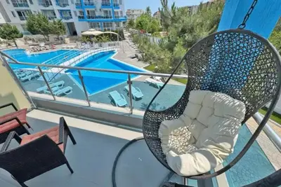 a chair on a balcony next to a swimming pool at Apartments Nessebar in Nesebar