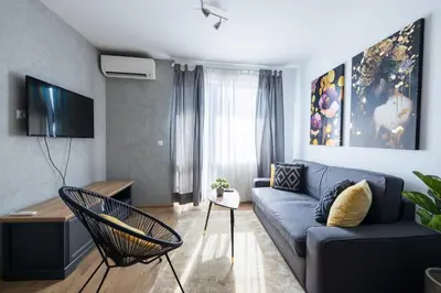 a living room with a blue couch and a tv at Chic Downtown Flat in Varna City