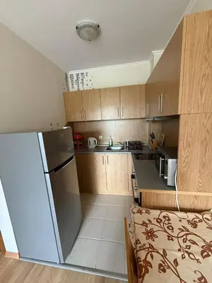 a small kitchen with wooden cabinets and a refrigerator at Pacific 3 Apartments in Sunny Beach