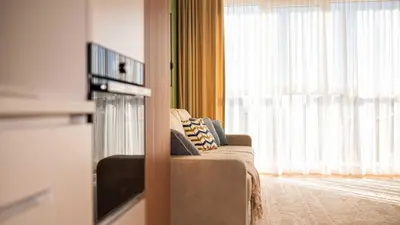 a living room with a couch and a large window at Harmony Delux Apartment -Free parking in Burgas City
