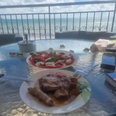 two plates of food on a table with a view of the ocean at Charming Studio at the Seaside in Aheloy