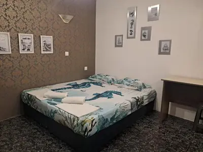 a bedroom with a bed and a desk and pictures on the wall at Бюджетна стая за двама in Pomorie