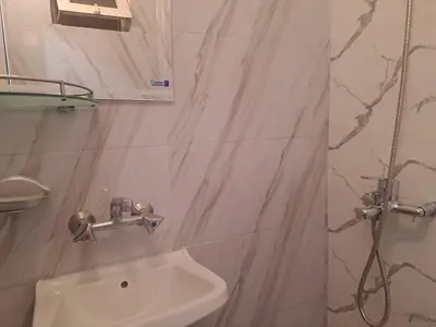a white bathroom with a sink and a shower at Бюджетна стая за двама in Pomorie