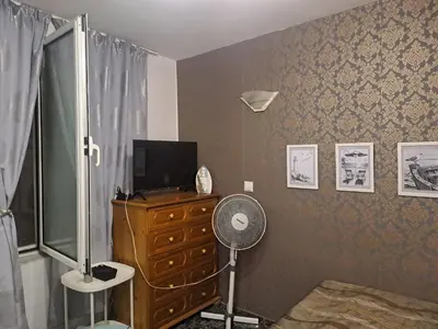 a room with a television and a dresser with a fan at Бюджетна стая за двама in Pomorie