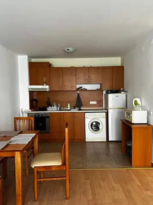 a kitchen with wooden cabinets and a table and chairs at Have a Good Rest Apartments in Sveti Vlas
